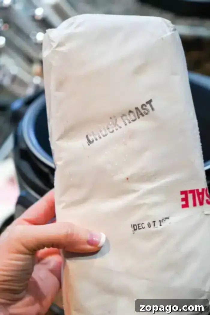 Fall Apart Slow Cooker Beef 3 A hand holds a wrapped package labeled "Chuck Roast," ideal for the slow cooker, with a visible sale sticker and a date marked "DEC 07 2023.