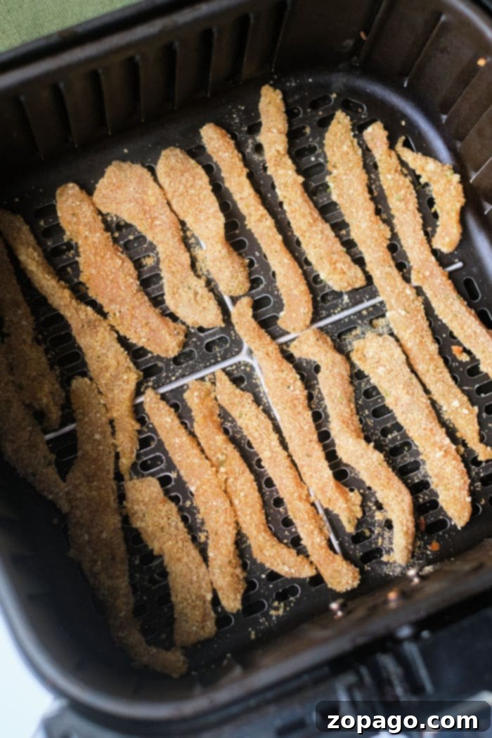 Crispy Air Fryer Chicken Fries 4 Ninja Foodi air fryer basket filled with homemade chicken fries and a side of french fries.