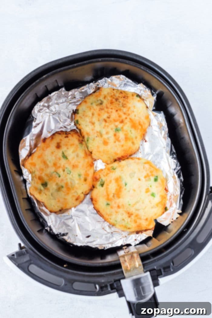 Crispy Air Fryer Potato Pancakes 6 Golden-brown and crispy air fryer potato pancakes resting on foil in the air fryer basket.