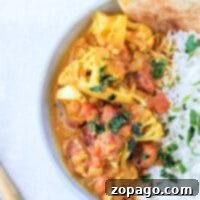 Savor a bowl of delectable Instant Pot cauliflower curry with rice and naan, beautifully garnished with fresh cilantro.