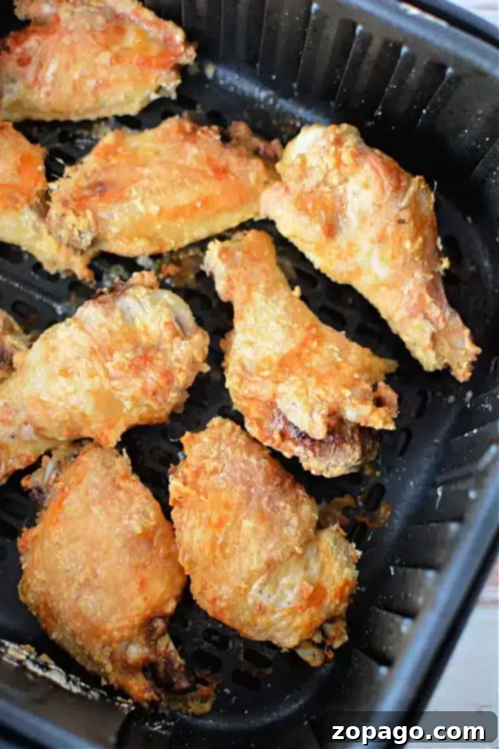 Crispy Air Fryer Chicken Wings with Baking Powder 9 Eight pieces of perfectly golden-brown and crispy air fryer chicken wings nestled in a black air fryer basket, showing off their textured, well-cooked surface, achieved with the baking powder method.