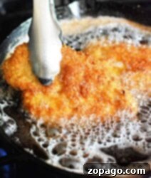 Unlock the Secret McChicken Recipe 8 Metal tongs holding a golden, breaded cutlet sizzling in bubbling oil, reminiscent of the crispy goodness of an Air Fryer McDonalds Fried Chicken Sandwich.