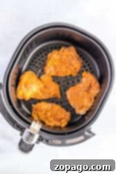 Unlock the Secret McChicken Recipe 9 Four seasoned chicken thighs sit invitingly in an air fryer basket, their crispy edges reminiscent of perfectly cooked fried chicken thighs.