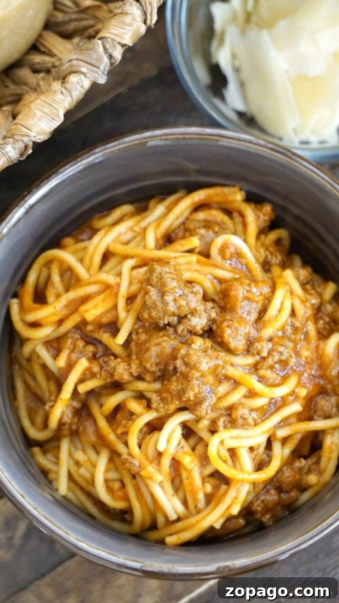 Achieving Al Dente Spaghetti 6 A bowl of instant pot spaghetti with savory meat sauce sits next to a delightful bowl of cheese and a charming wicker basket.