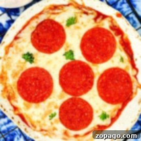 A freshly made Air Fryer Tortilla Pizza with melted cheese, six pepperoni slices, and a sprinkle of parsley, presented on a wire rack next to a pizza cutter.