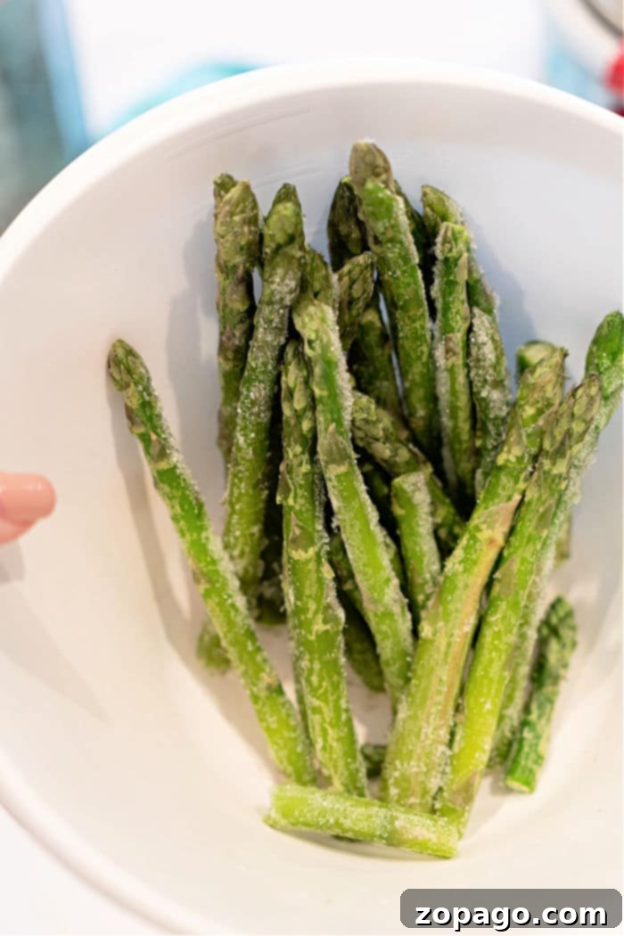 Easy Air Fryer Frozen Asparagus 5 A serving of air-fried frozen asparagus, perfectly golden and tender-crisp, garnished with fresh herbs, suggesting a delicious way to cook frozen asparagus.