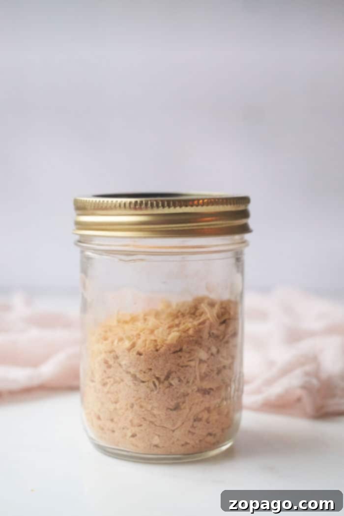 Homemade Lipton French Onion Soup Mix 5 A clear jar with a gold lid, filled with homemade French Onion Soup Mix, rests elegantly on a white surface.