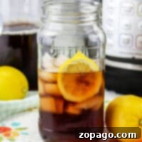 A mason jar filled with iced tea and a lemon slice sits amidst fresh lemons, hinting at the secret of how to make sweet tea with Lipton tea bags. An appliance hums softly in the background, promising more refreshing sips to come.