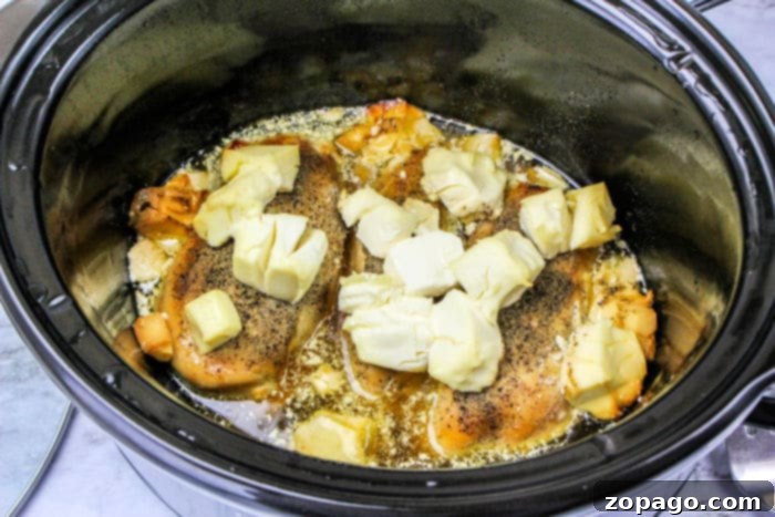 Gourmet Cordon Bleu Chicken Melt 4 Slow cooker filled with boneless chicken breasts, cream cheese, and seasonings, ready for cooking.