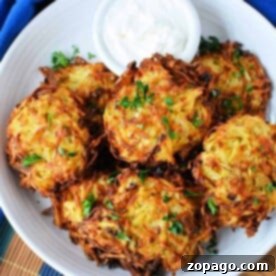 Plate of crispy air fryer latkes garnished with parsley, served with a small bowl of sour cream on a wooden table.