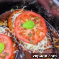 Crockpot chicken made with frozen breasts, melted cheese, sliced tomatoes, and herbs offers a convenient and delicious meal from your slow cooker.