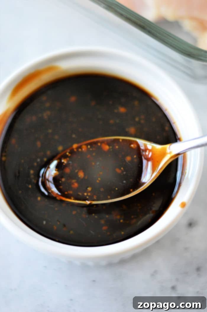Deliciously Simple Teriyaki Chicken 6 A white bowl filled with dark, thick homemade teriyaki sauce, garnished with sesame seeds.