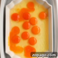 A white rectangular dish displays raw egg yolks and whites, showcasing an inviting simplicity reminiscent of no peel hard boiled eggs.