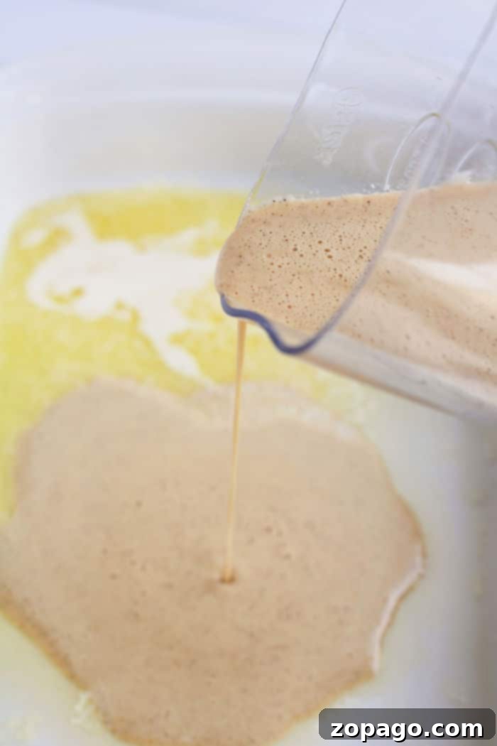 Oven-Baked Pancakes 5 Homemade German pancake batter in a glass measuring cup, ready to be poured.