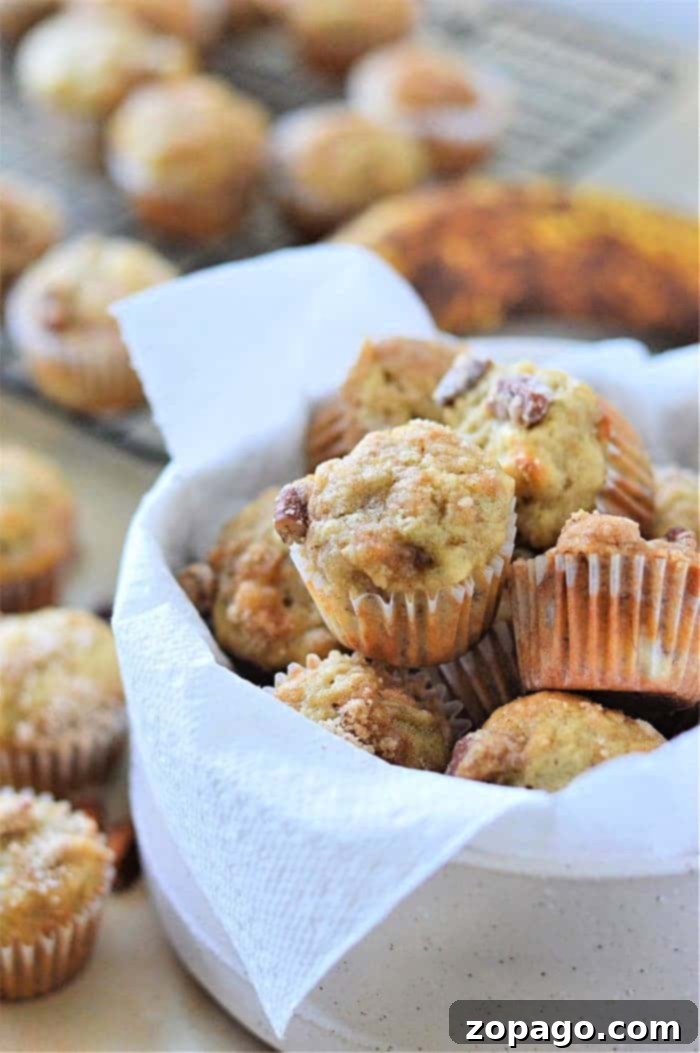 Spiced Mini Pumpkin Muffins 9 A white bowl filled with freshly baked mini muffins, lined with a napkin, rests invitingly on the table.