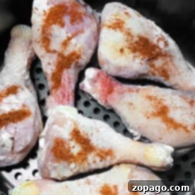 Six raw, seasoned chicken drumsticks, perfect for making Frozen Chicken Legs in Air Fryer, are placed in the basket and ready to be cooked.