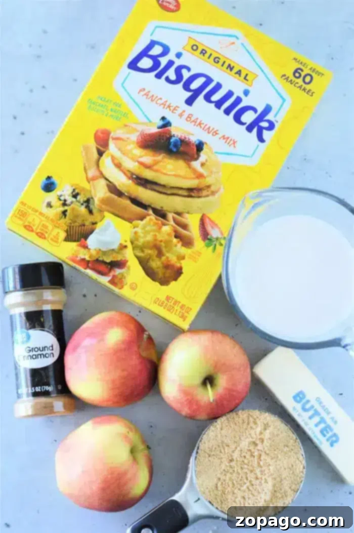 Easy Bisquick Apple Cobbler 3 A box of Bisquick Pancake and Baking Mix is surrounded by a measuring cup with milk, a bottle of ground cinnamon, three apples, a stick of butter, and a measuring cup filled with brown sugar on a light-colored surface—everything you need for an easy Apple Cobbler with Bisquick.