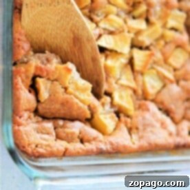 A wooden spoon serving a piece of baked apple cinnamon cake from a glass dish, reminiscent of a classic Apple Cobbler with Bisquick.