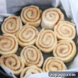 Unbaked Slow Cooker Cinnamon Rolls arranged in a round baking pan lined with parchment paper.
