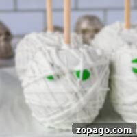 Ghostly White Chocolate Halloween Apples 7 Halloween candy apples are ghoulishly delightful, decorated like mummies with white chocolate wrappings and eerie green eyes. Presented on a plate with a zigzag-patterned napkin, they make the perfect spooky treat.