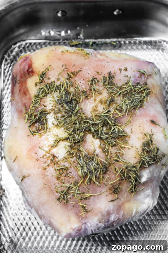 Oven Baked Frozen Chicken 4 Close-up of a beautifully seasoned, whole frozen chicken on a roasting rack, highlighting the preparation steps for cooking a whole frozen chicken in the oven.
