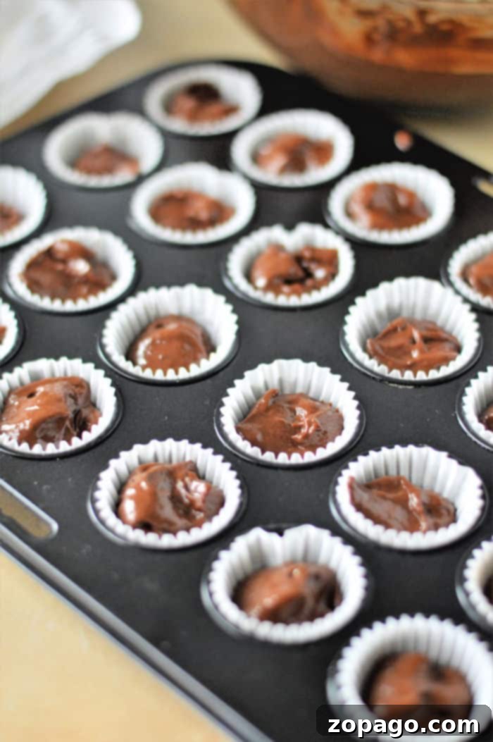 Bite-sized Chocolate Indulgences 7 A large batch of frosted mini chocolate chip muffins with an additional dollop of frosting on top.