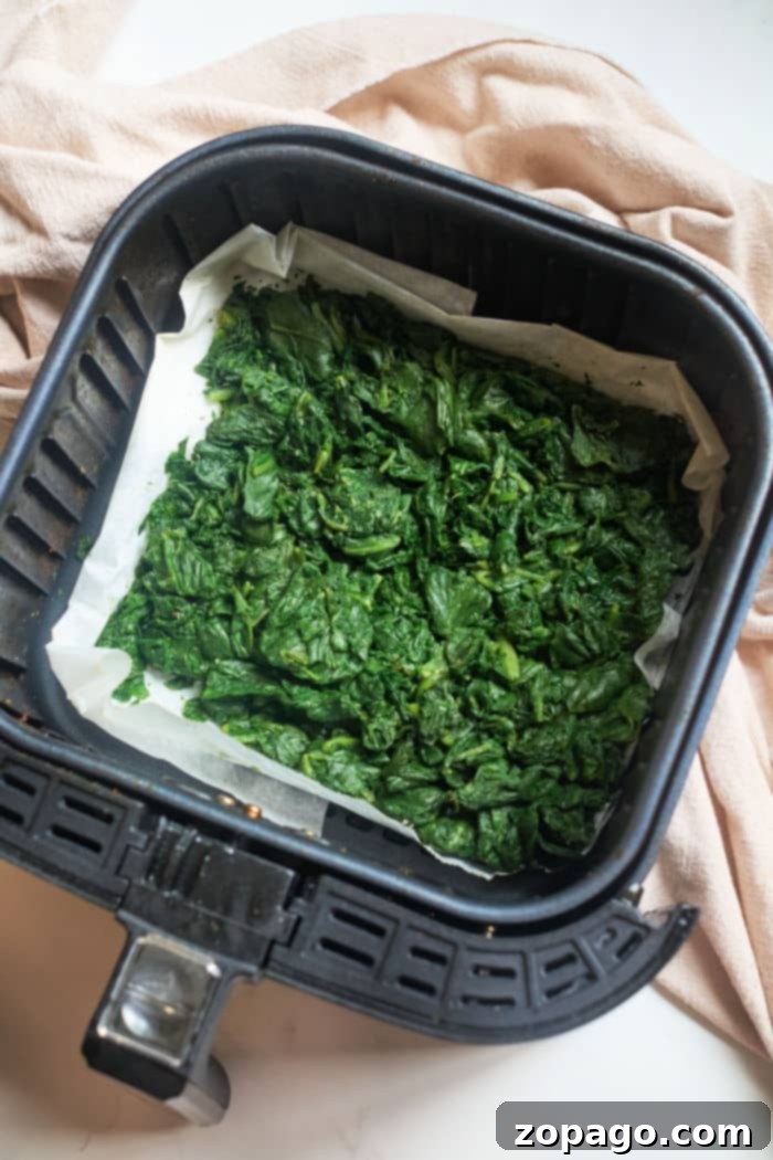 Make Frozen Spinach Taste Amazing 6 Air fryer basket filled with cooked frozen spinach, perfectly tender and seasoned.
