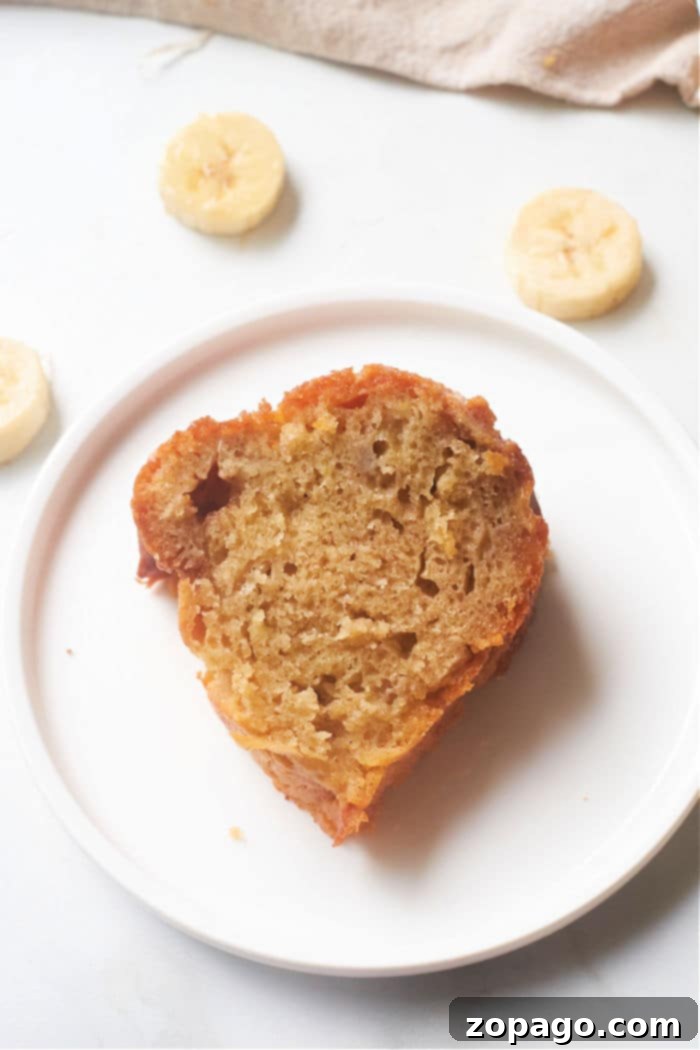 A whole moist banana bundt cake, golden brown and perfectly baked, on a serving plate.