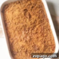 A white baking dish holds a freshly baked banana coffee cake with a crumb topping, resting invitingly on a light countertop.