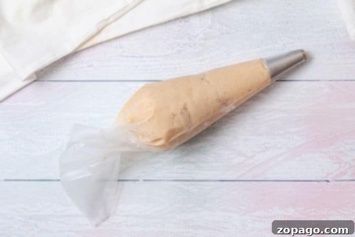 Air Fryer Lava Chocolate Churros 4 A piping bag filled with churro dough lies invitingly on a white wooden surface, ready to make air fryer chocolate-filled churros.