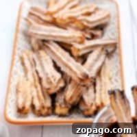 Air Fryer Chocolate Churro Delights 8 A stack of air fryer churros, filled with rich chocolate, sits on a patterned plate, with a bowl of extra chocolate sauce nearby for dipping.