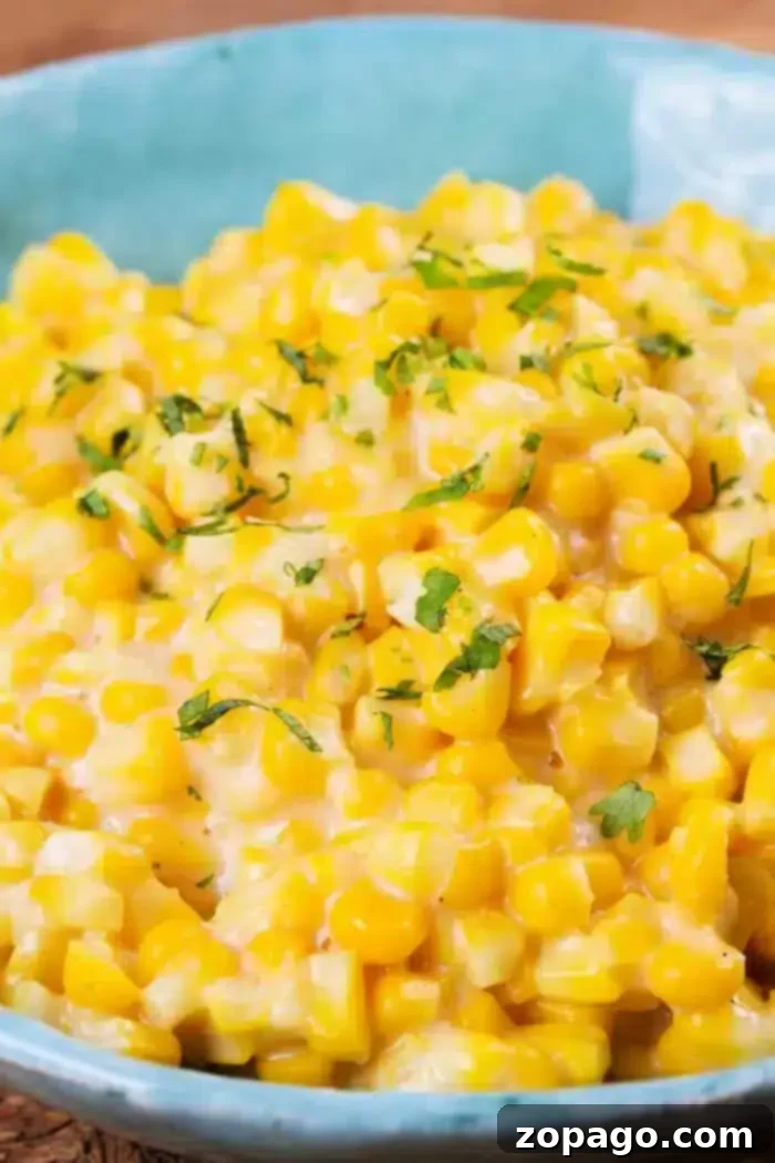 Golden Honey Butter Skillet Corn 2 A blue bowl brims with creamy Honey Butter Skillet Corn, topped with chopped green herbs. The dish looks indulgent and richly garnished, hinting at a luscious sauce or dressing that enhances its flavor.