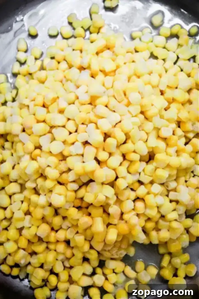 Golden Honey Butter Skillet Corn 3 A close-up view of a heap of fresh or possibly frozen yellow and white corn kernels, piled on a dark surface, promises the delicious potential of Honey Butter Skillet Corn.