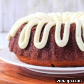 Displayed on a white plate and wooden board, this Bundt cake features a luscious cream frosting drizzled on top. But what is a Bundt cake? Its a beautifully molded cake baked in a distinctive ring-shaped pan that adds elegance to any table.