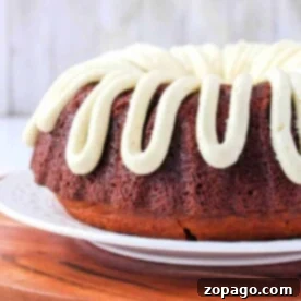 Displayed on a white plate and wooden board, this Bundt cake features a luscious cream frosting drizzled on top. But what is a Bundt cake? Its a beautifully molded cake baked in a distinctive ring-shaped pan that adds elegance to any table.