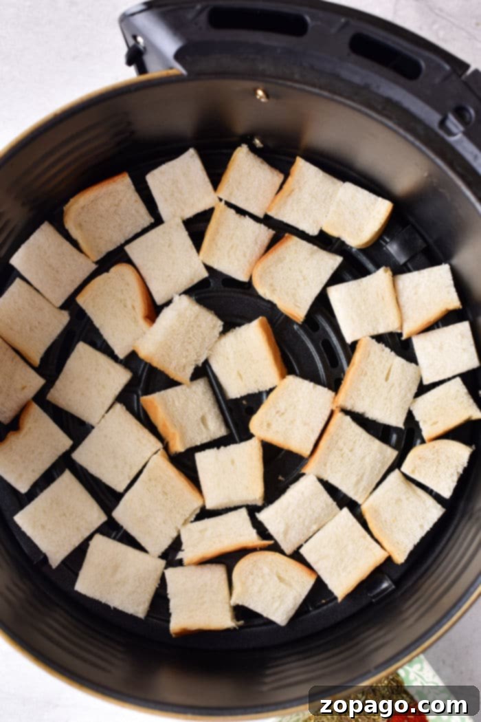 Crumbly Perfection From Your Kitchen 3 Air fryer basket filled with toasted bread cubes, ready for crushing into breadcrumbs.