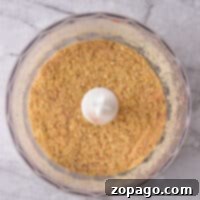 Crumbly Perfection From Your Kitchen 6 Top view of a food processor bowl containing finely ground seasoned breadcrumbs on a gray marble surface.