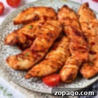 Savor the delicious chicken tenders on a plate, perfectly paired with cherry tomatoes and fresh herbs. For a quick alternative, try using frozen chicken tenderloins in the air fryer for equally tasty results.
