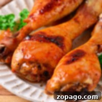 Baked chicken drumsticks, perfectly cooked to juicy perfection, rest on a plate with a parsley garnish. Wondering how long to bake chicken drumsticks at 400 degrees? This dish captures the essence of both methods for delightful tenderness.