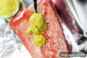 Crispy Air Fryer Corned Beef 6 A spoon drizzles yellow mustard sauce over a thick, raw cut of Air Fryer Corned Beef on foil.