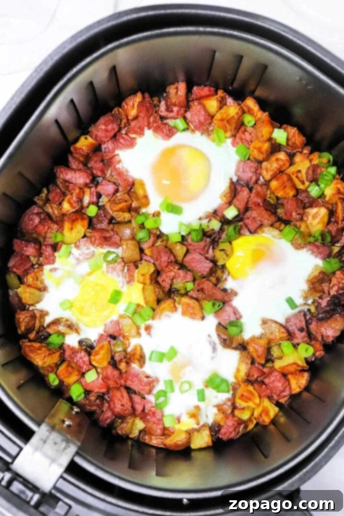 Crispy Air Fryer Corned Beef Hash 9 Close up view of air fryer corned beef hash with fried eggs, garnished with fresh chives, ready to eat for breakfast.