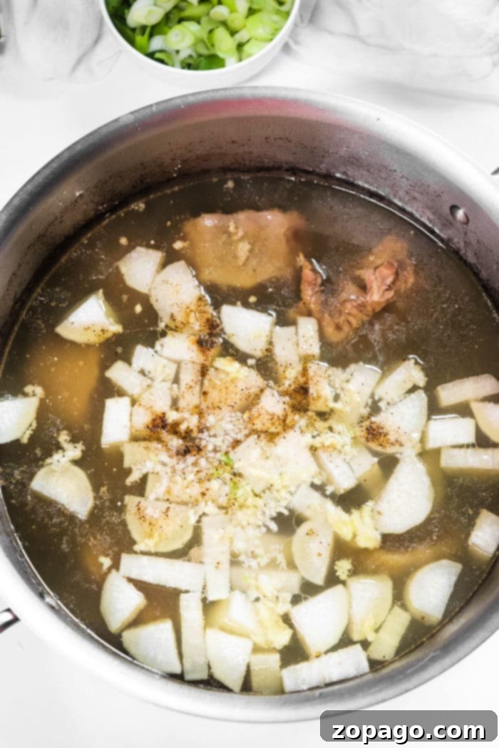 Korean Oxtail Soup 4 A large stock pot filled with simmering Korean Oxtail Soup, featuring tender oxtail pieces, daikon radish, and green onions.