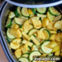 Air Fryer Squash and Zucchini perfectly illustrate the blend of convenience and taste, with sliced zucchini and squash arranged in an air fryer basket for a quick, healthy treat.