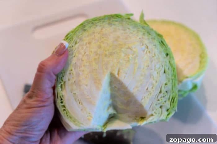 Crispy Air Fryer Cabbage 4 A close-up image showing the process of cutting the tough core stem out of a head of cabbage, preparing it for slicing or cubing.