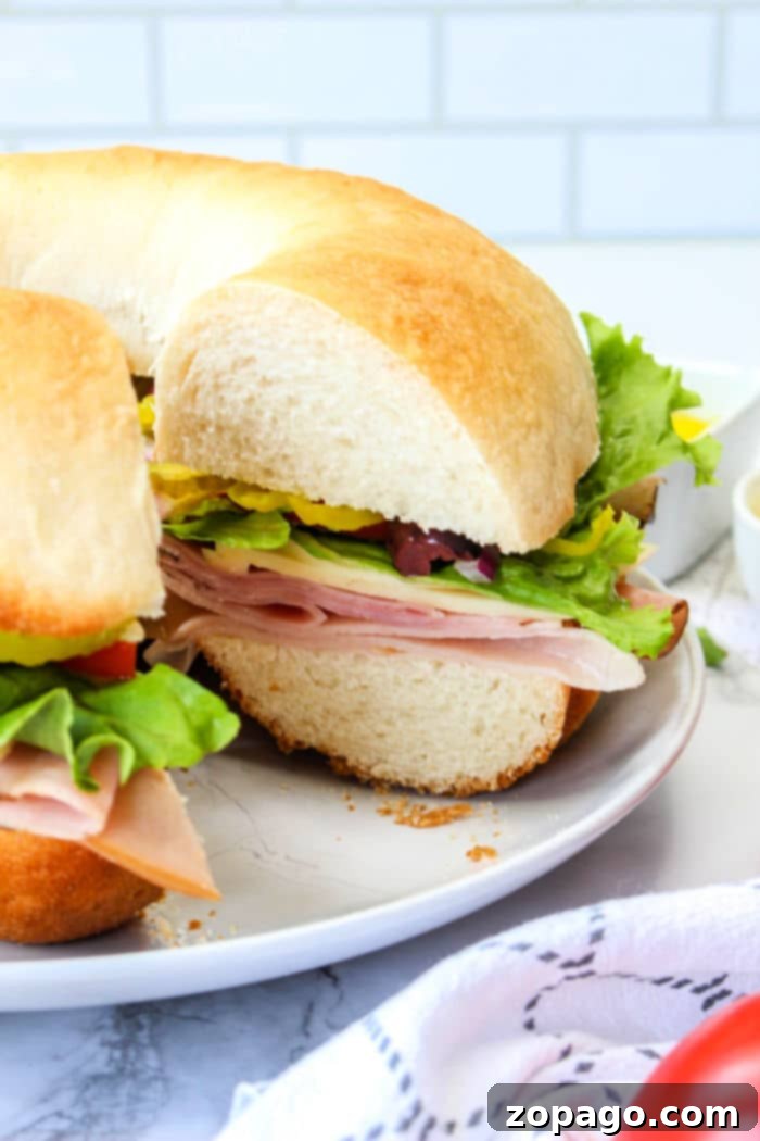Crownwich 7 A sliced bundtwich sandwich with ham, lettuce, and vegetables on a white plate resembles an artisanal take on how to make a bundtwich.