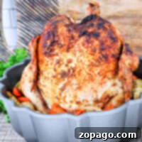 Rotisserie chicken in an oven-fresh gray bundt pan with vegetables, placed on a textured surface and framed by a rustic wooden backdrop.