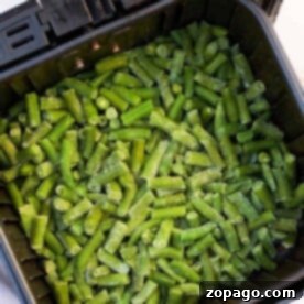 Experience the effortless cooking of air fryer frozen green beans, nestled perfectly inside the basket.