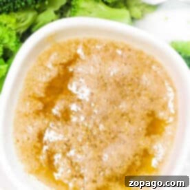 A bowl of Cajun Garlic Butter Sauce next to steamed broccoli florets with a fork, representing the recipe.