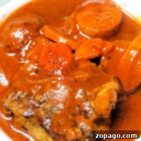 A bowl of rich, red Instant Pot Oxtail Soup, brimming with tender meat, carrots, and potatoes.