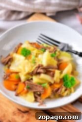 Hearty Cabbage Stew 8 Plate of corned beef with a cabbage stew twist, complemented by carrots and garnished with parsley, all elegantly presented on a wooden surface.